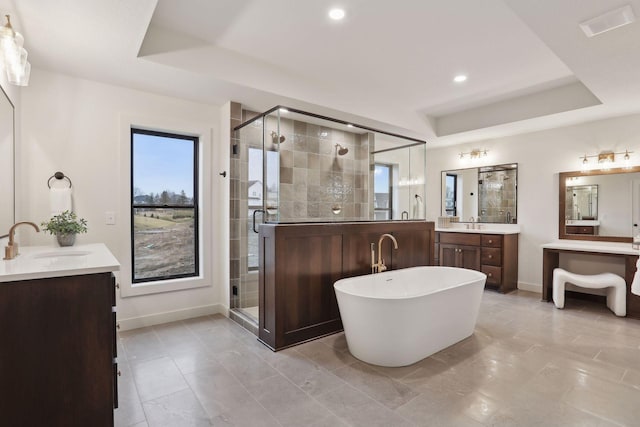 bathroom with vanity, a tray ceiling, and separate shower and tub