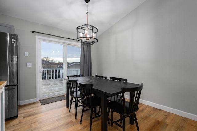 dining room featuring a notable chandelier, baseboards, and light wood finished floors