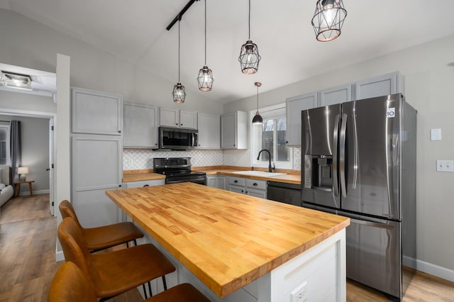 kitchen with butcher block countertops, gray cabinetry, a sink, tasteful backsplash, and appliances with stainless steel finishes