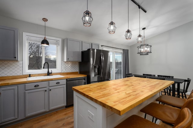 kitchen with refrigerator with ice dispenser, gray cabinets, a sink, wood counters, and dishwasher