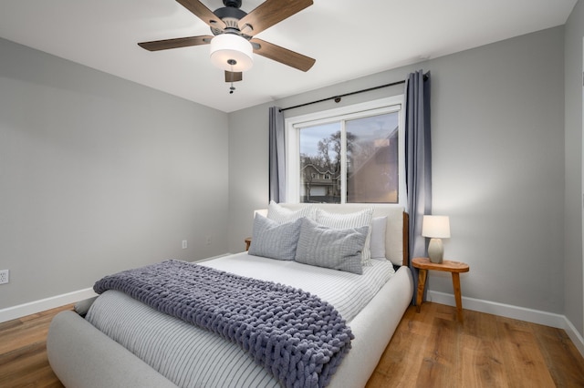 bedroom with ceiling fan, baseboards, and wood finished floors