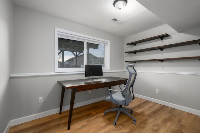 office space with visible vents, baseboards, a textured ceiling, and wood finished floors