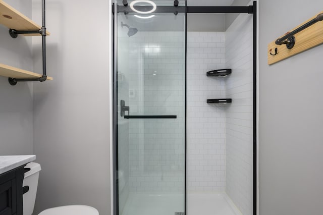 bathroom featuring toilet, a stall shower, and vanity