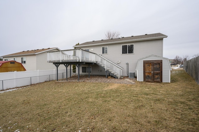 back of property with a deck, stairway, fence, and a lawn