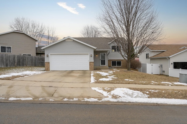 split level home with brick siding, concrete driveway, and fence