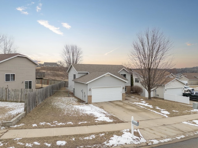 ranch-style home with brick siding, an attached garage, fence, roof with shingles, and driveway