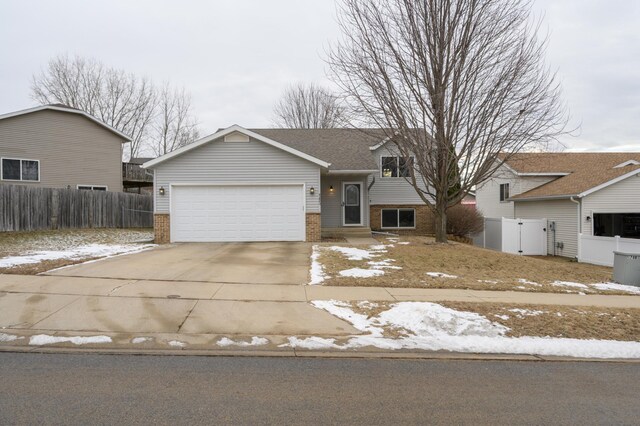 split level home featuring fence, brick siding, and driveway