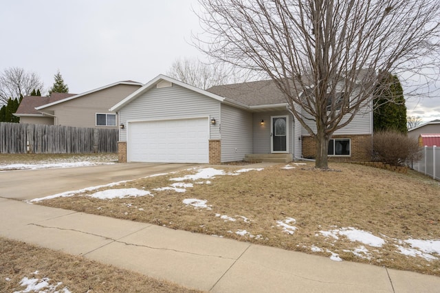 ranch-style home with brick siding, an attached garage, driveway, and fence