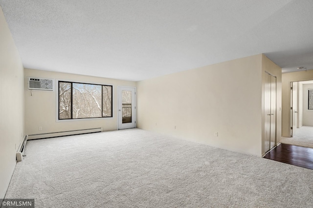 spare room with a textured ceiling, carpet floors, a baseboard radiator, and a wall mounted AC