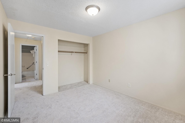 unfurnished bedroom featuring light carpet, a closet, and a textured ceiling