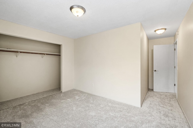 unfurnished bedroom with light colored carpet, a textured ceiling, and a closet