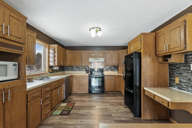 kitchen with sink, dark hardwood / wood-style flooring, decorative backsplash, black appliances, and a textured ceiling