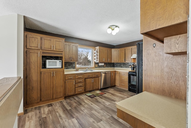 kitchen featuring hardwood / wood-style floors, tasteful backsplash, sink, and stainless steel dishwasher