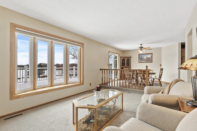 carpeted living room with ceiling fan, plenty of natural light, and a textured ceiling