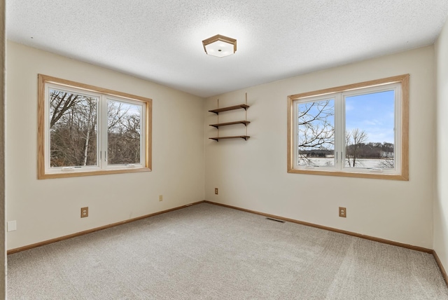 carpeted empty room featuring a textured ceiling