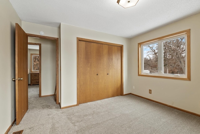 unfurnished bedroom featuring light colored carpet, a closet, and a textured ceiling