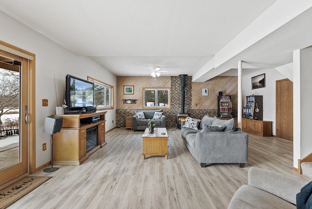 living room featuring a fireplace, light wood-type flooring, wood walls, and a wood stove