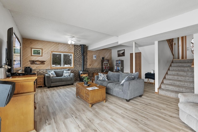 living room with a wood stove, light hardwood / wood-style floors, and wood walls