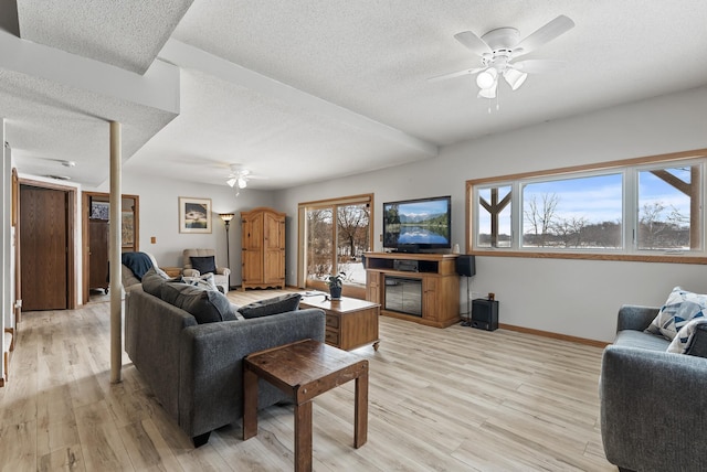 living room with a textured ceiling, light hardwood / wood-style flooring, and ceiling fan