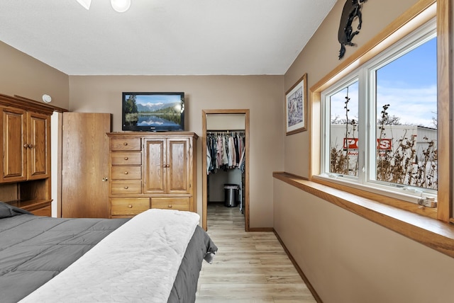 bedroom with a closet, a walk in closet, and light hardwood / wood-style flooring