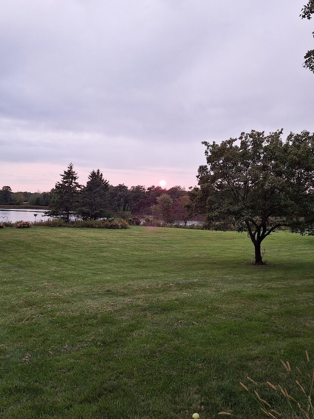 yard at dusk featuring a water view