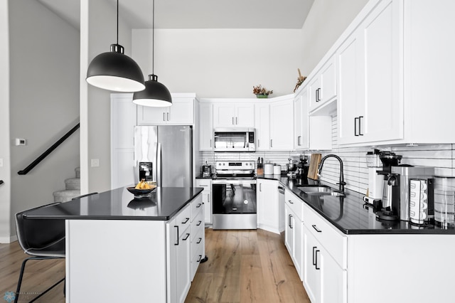 kitchen with pendant lighting, stainless steel appliances, sink, and white cabinets