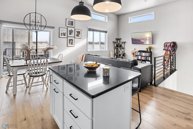 kitchen featuring pendant lighting, a kitchen breakfast bar, a center island, white cabinets, and light wood-type flooring