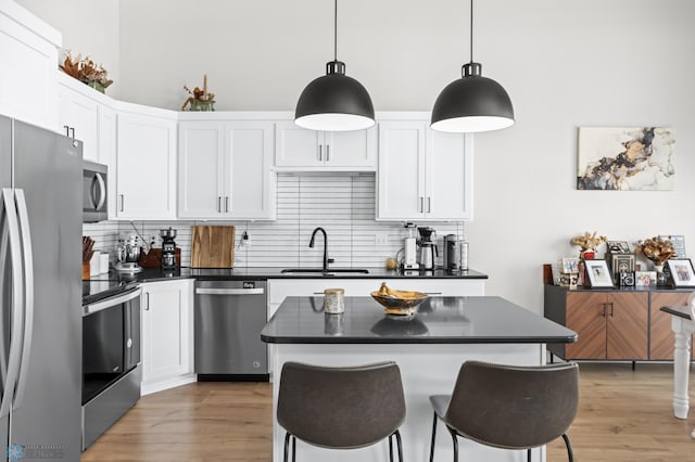 kitchen with stainless steel appliances, white cabinetry, hanging light fixtures, and sink