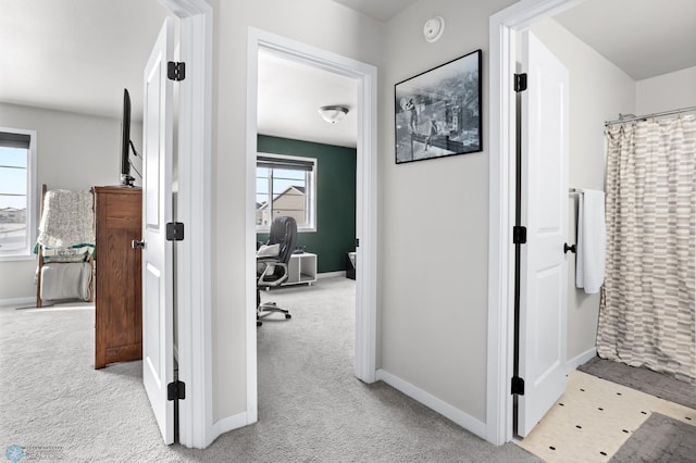 hall featuring light colored carpet and a wealth of natural light