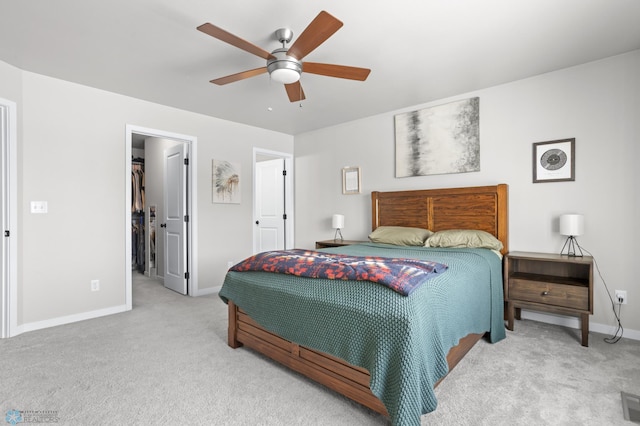 bedroom featuring a spacious closet, light carpet, ceiling fan, and a closet