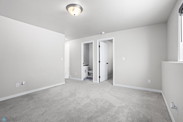 unfurnished bedroom featuring light colored carpet and ensuite bathroom