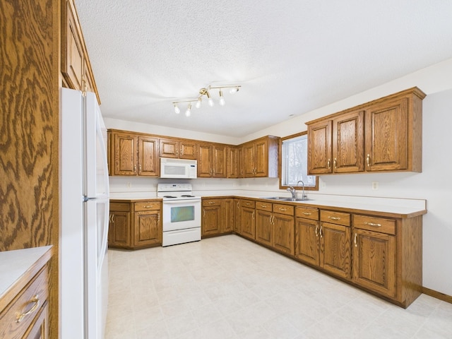 kitchen featuring brown cabinets, a sink, a textured ceiling, white appliances, and light countertops