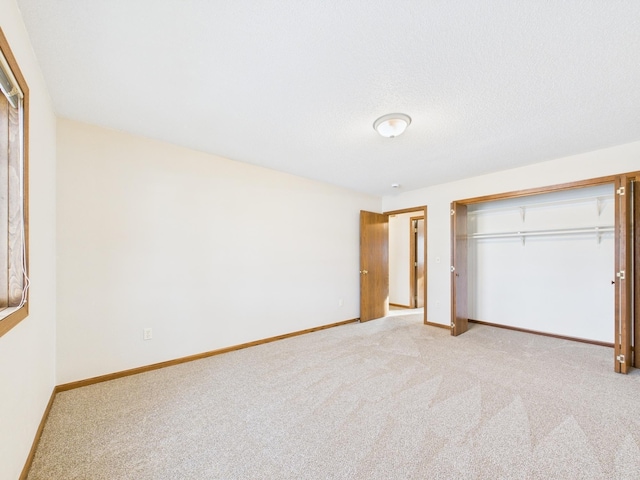 unfurnished bedroom featuring carpet, baseboards, a closet, and a textured ceiling