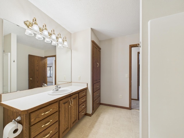 bathroom with a textured ceiling, vanity, and baseboards