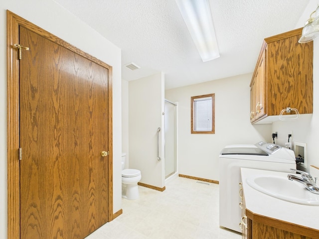 full bathroom featuring visible vents, washing machine and clothes dryer, a stall shower, a textured ceiling, and toilet