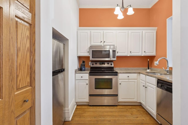 598 Summit Ave Unit 1, Saint Paul, MN 55102 - kitchen with appliances with stainless steel finishes, a chandelier, a sink, crown molding, and white cabinets