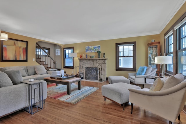 living room with ornamental molding, a stone fireplace, and hardwood / wood-style floors