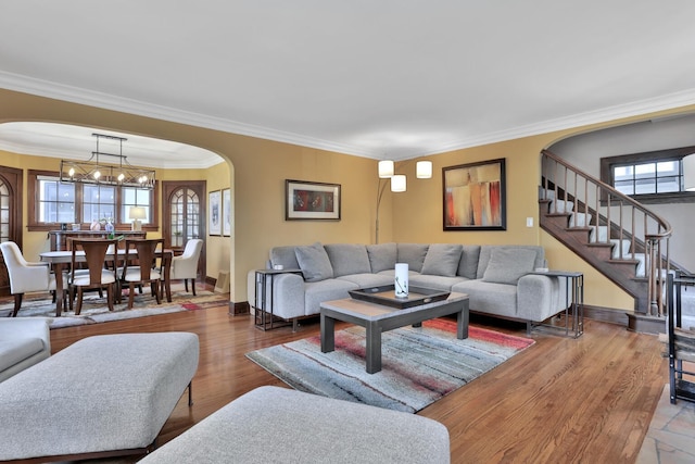 living room with wood-type flooring, a notable chandelier, and crown molding