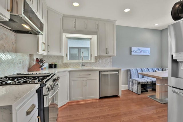 kitchen featuring sink, tasteful backsplash, light hardwood / wood-style flooring, stainless steel appliances, and white cabinets