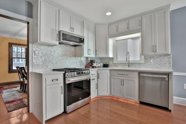 kitchen with white cabinetry, stainless steel appliances, sink, and light wood-type flooring