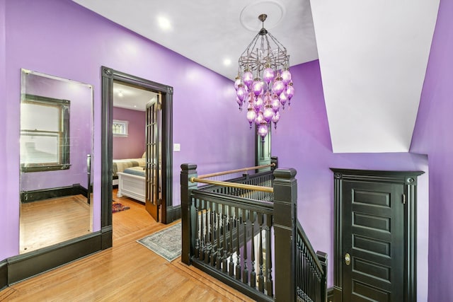 corridor featuring recessed lighting, an inviting chandelier, an upstairs landing, wood finished floors, and baseboards