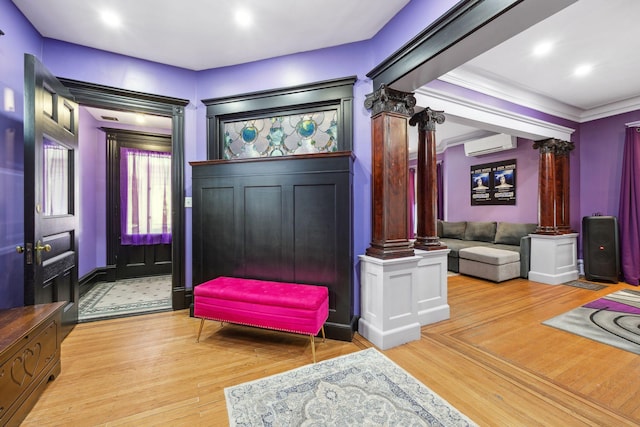 entrance foyer with light wood-style floors, ornate columns, and a wall mounted AC