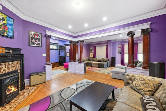 living area featuring crown molding, wood finished floors, and ornate columns