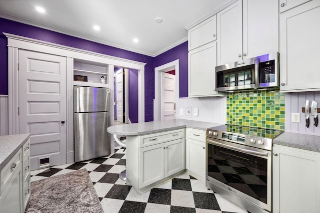 kitchen featuring a peninsula, dark floors, white cabinets, and stainless steel appliances