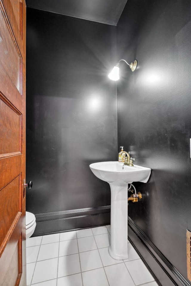 bathroom with baseboards, toilet, and tile patterned floors