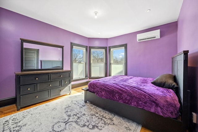 bedroom featuring a wall unit AC and light wood-style flooring