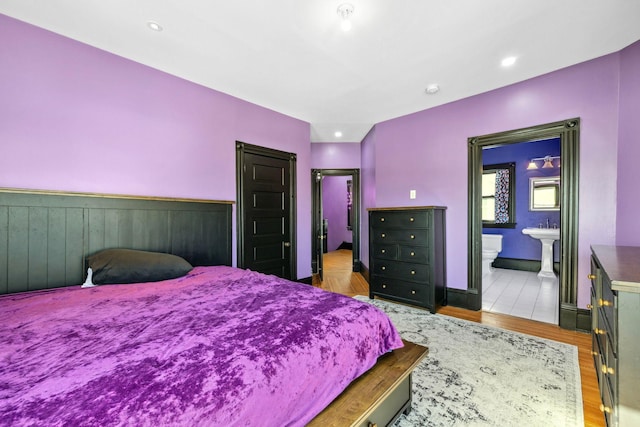 bedroom featuring recessed lighting, wood finished floors, and connected bathroom