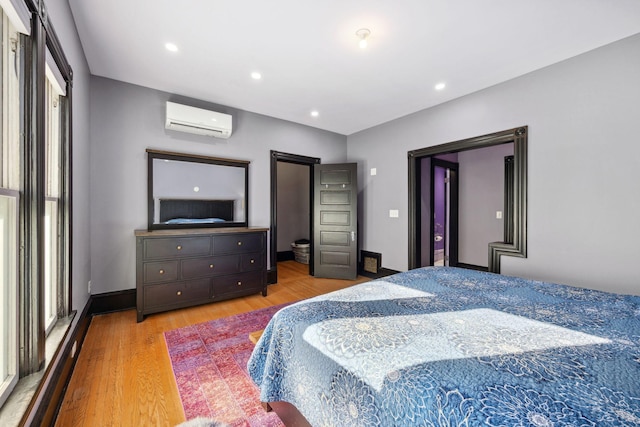 bedroom featuring a wall unit AC, light wood finished floors, recessed lighting, multiple windows, and baseboards