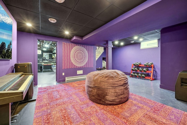 home theater with finished concrete flooring, baseboard heating, and a drop ceiling