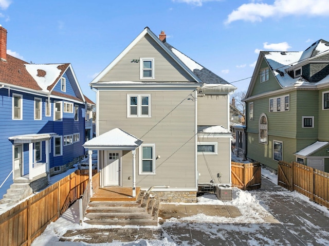 snow covered rear of property with a fenced backyard and a residential view